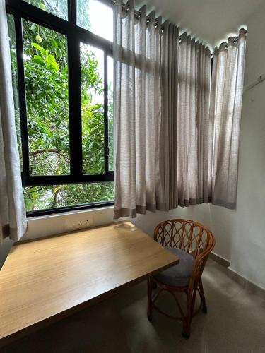 a wooden table and a chair in front of a window at 1 BHK Fully Furnished - Soorya Madhavam Apartments - Flat No - C2 - Guruvayur, - 150m to North Nada - Family only in Guruvāyūr