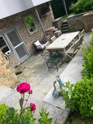 a patio with a wooden table and a bird statue at Maison et son jardin situés dans le Condroz in Marchin