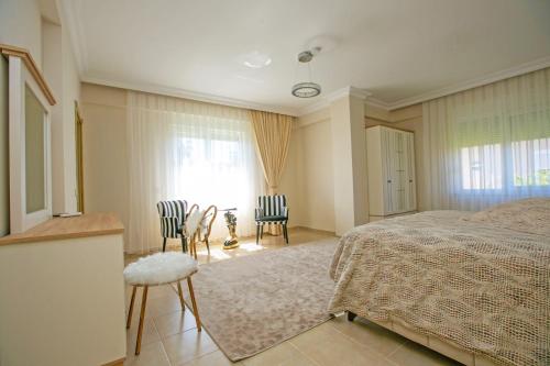 Un dormitorio con una cama y dos sillas y una ventana. en Paradise Town Villa Hazel, en Belek