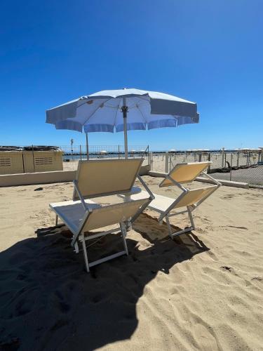 two lounge chairs and an umbrella on the beach at VillaBaci sul Mare - Spiaggia privata in Rimini