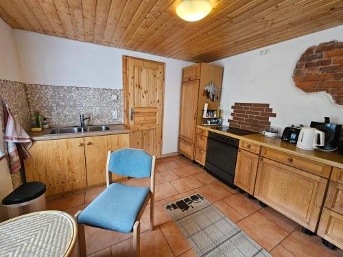 a kitchen with wooden cabinets and a blue chair at Idyllisches Ferienhaus im Fichtelgebirge in Nagel