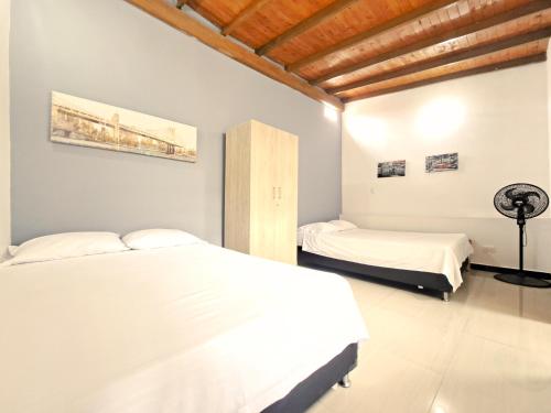 2 camas num quarto com paredes brancas e tectos em madeira em Beautiful and cozy house in the best location em Medellín