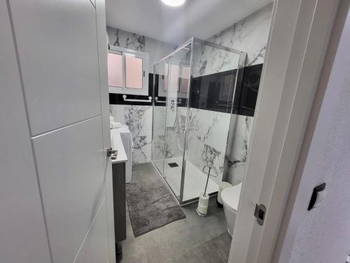 a white bathroom with a toilet and a shower at 2 Bedrooms Flat + Balcony + Parking at Las Canteras Beach in Las Palmas de Gran Canaria