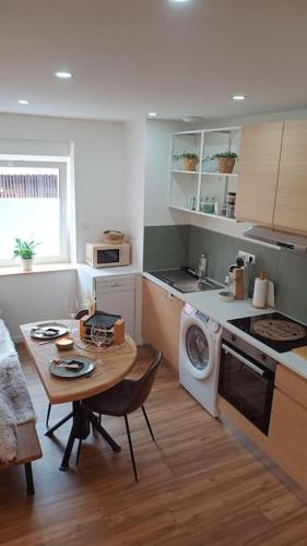 une cuisine avec une table et une machine à laver dans l'établissement Le Physalis gîte tout confort, à Orbey