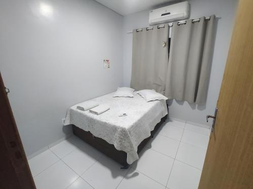 Cette petite chambre blanche comprend un lit et un rideau. dans l'établissement Piscina, Hidro, churrasqueira em casa, ambas privativas - Reserva 2 quartos com ar, 2 banheiros, sala,cozinha e pátio privativos, para moradia memorável ou evento, acesse descontão por duração!, à Sorriso