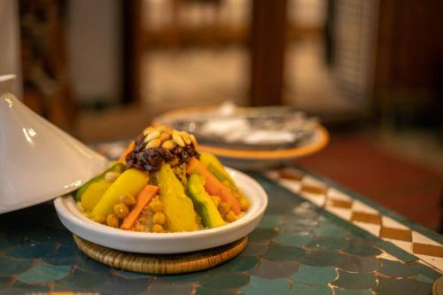 a bowl of vegetables on a table with a spoon at Dar Authentic Fes - familly hosting in Fès