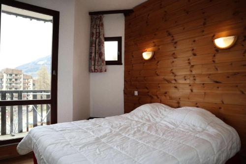 une chambre avec un lit et un mur en bois dans l'établissement Residence Le 1650 - Bel appartement pour 10 personnes cœur de station MAE-5861, aux Orres