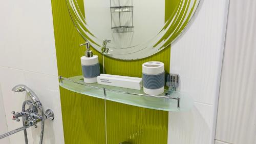 a bathroom with a green wall with a mirror at PANORAMIC view apartment in Tashkent