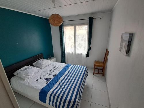 Cet appartement comprend une chambre dotée d'un lit avec un mur bleu et une fenêtre. dans l'établissement maison individuelle bassin arcachon, au Teich