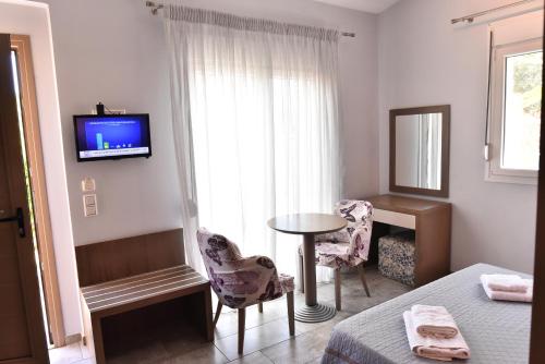 1 dormitorio con mesa, sillas y TV en Thalassa Apartments, en Skala Potamias