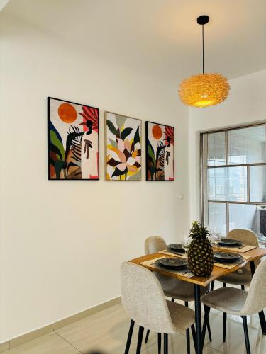a dining room table with chairs and paintings on the wall at Confort au centre ville in Libreville