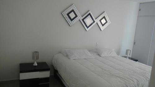 a bedroom with a bed and three pictures on the wall at Apartamento Los Morros in Cartagena de Indias