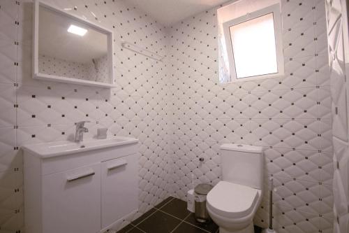 a bathroom with a toilet and a sink and a window at Arber's Home in Sarandë