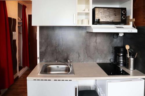 une cuisine avec un évier et un micro-ondes dans l'établissement Residence Le 1650 - Studio pour 2 personnes cœur de station des Orres 1650 MAE-5941, aux Orres