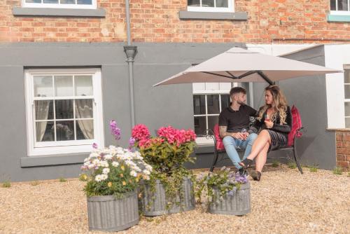 a man and a woman sitting under an umbrella at The Boat House Luxury Apartments Scarborough in Scarborough