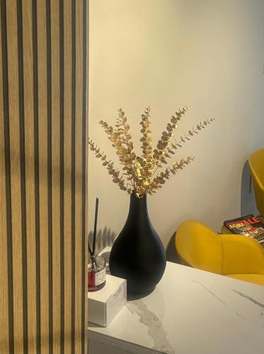 a black vase with flowers in it on a table at Narciso boutique apartment in Acireale