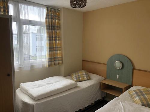 two twin beds in a room with a window at Villa 118 Dawlish Warren in Dawlish Warren