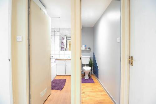 baño con aseo y pasillo con puerta en Comfy private room in Battersea close to Clapham Junction, en Londres