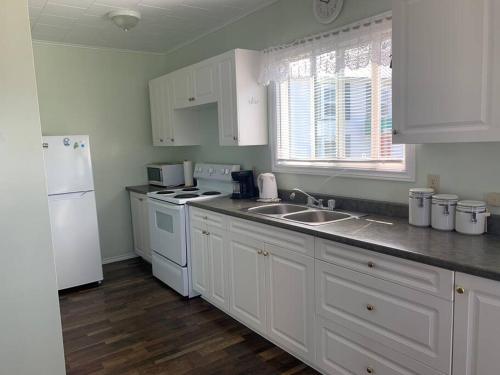 a kitchen with white cabinets and a white refrigerator at Hillside Cottage in Twillingate