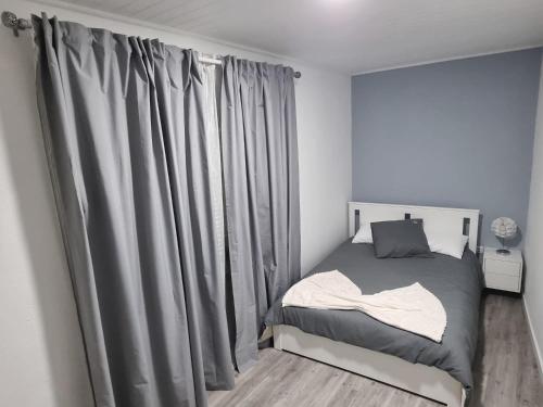 una piccola camera da letto con un letto con tende grigie di Casa Pereira 2 a Ponta do Pargo