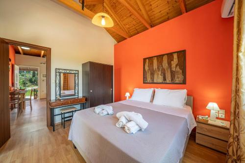a bedroom with orange walls and a bed with towels at Moudilos 1 in Lixouri