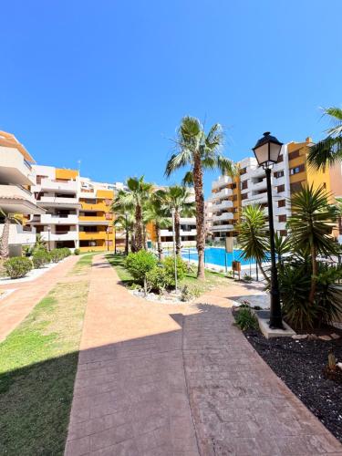 a walkway with palm trees and a building at La Recoleta Residence Punta Prima in Torrevieja