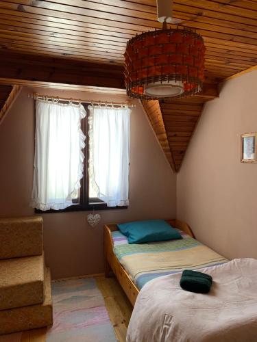 a bedroom with two beds and two windows at Zlatiborska kuća u šumi in Dobroselica