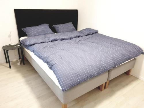 a bed with a blue comforter and two pillows at Spacious 2 Bedroom Apartment in Arendal. in Arendal