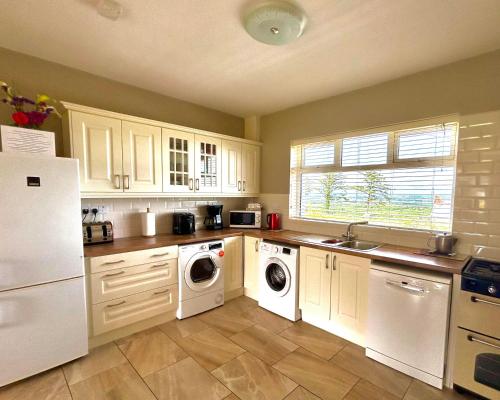 een keuken met een witte koelkast, een wasmachine en een droger bij Breenville Farm House in Tralee