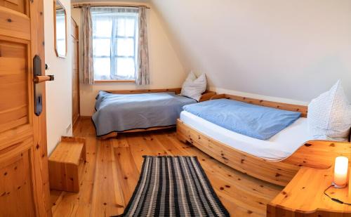 a bedroom with two beds and a wooden floor at Reetdachhäuser gegenüber Hiddensee in Schaprode