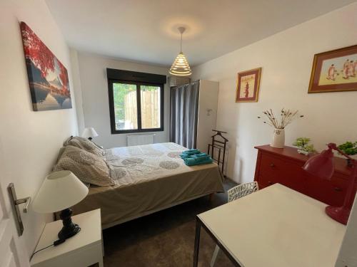 une petite chambre avec un lit et une table dans l'établissement Au parfum des fleurs, à Saint-Médard-en-Jalles