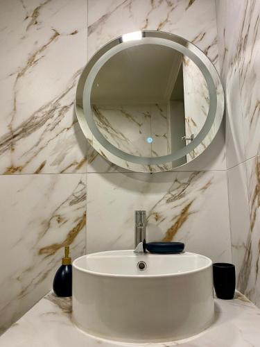 a bathroom sink with a round mirror on the wall at Oneiropetra Luxury House in Argalasti