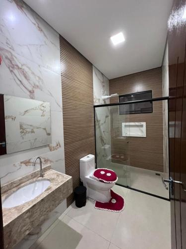 a bathroom with a toilet and a sink at Casa Suítes Beach in Vilhena