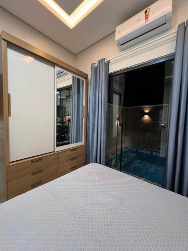 a bedroom with a large window and a swimming pool at Casa Suítes Beach in Vilhena