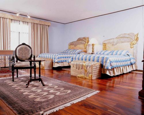 1 dormitorio con 2 camas, silla y escritorio en Hotel Portal del Angel, en Tegucigalpa