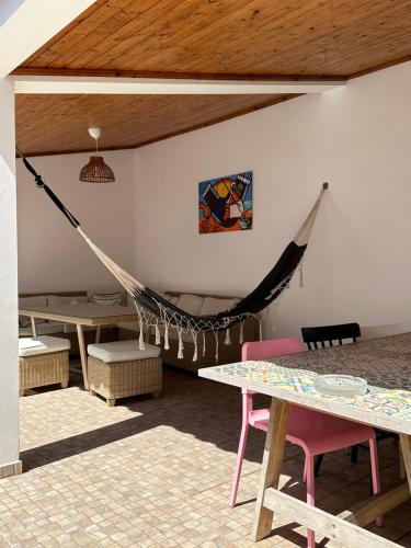 a hammock in a room with a table and tables at Pirata Milfontes Guest House in Vila Nova de Milfontes