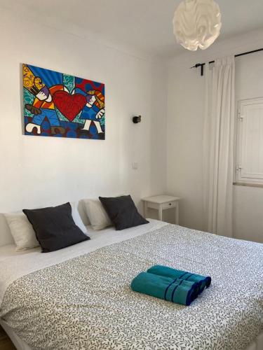 a bed in a bedroom with a painting on the wall at Pirata Milfontes Guest House in Vila Nova de Milfontes