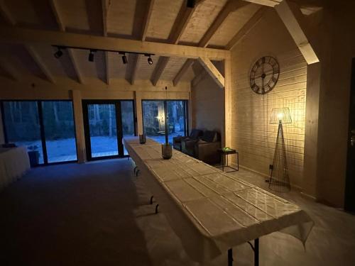 a large room with a table and a clock on the wall at DOMKI Leśna Cisza jezioro Powidzkie dla 18 osób - 5D Apartments in Lipnica