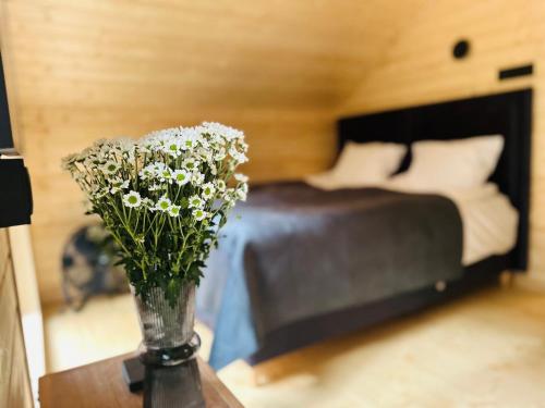 a vase of flowers on a table in a bedroom at DOMKI Leśna Cisza jezioro Powidzkie dla 18 osób - 5D Apartments in Lipnica