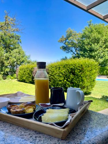 una bandeja de comida en una mesa con una botella de zumo de naranja en Bosque da Harmonia, en Arco de Baúlhe