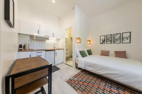une chambre blanche avec un lit et une cuisine dans l'établissement Le 288 - Appartements Reimois, à Reims