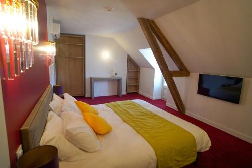 a bedroom with a large bed with yellow pillows at Hôtel de la Croix Blanche in Villiers-Saint-Benoît