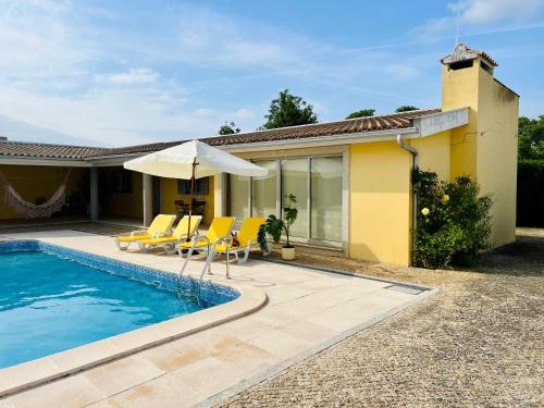 a pool with chairs and an umbrella next to a house at A Casa do Pai Carlos in Salreu