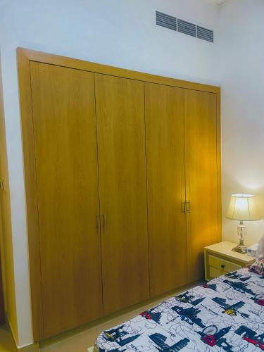 a large wooden cabinet in a bedroom with a bed at Emirates apartment in Dubai