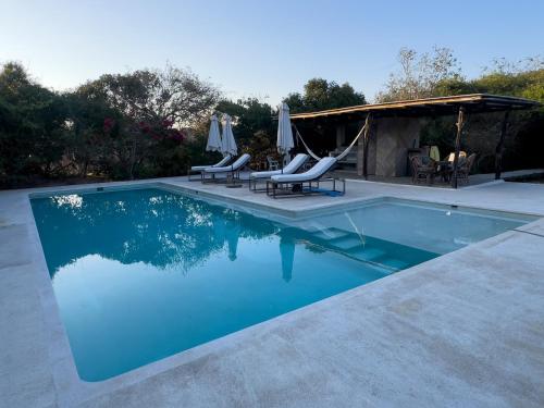a swimming pool with chairs and a gazebo at Casita Flor de Mayo in Santa María Colotepec