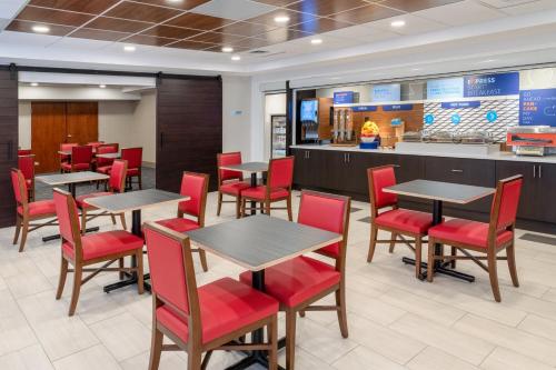 a dining room with tables and red chairs at Holiday Inn Express & Suites Colorado Springs-Airport by IHG in Colorado Springs