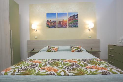 una camera da letto con un letto e due dipinti alle pareti di Kris Luxury Apartments a Giardini Naxos