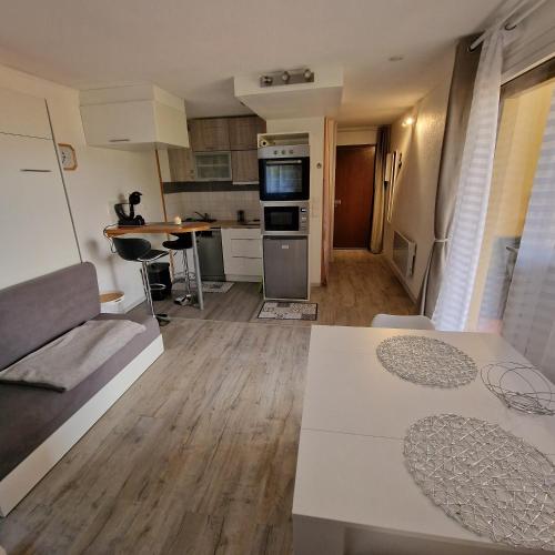 un salon avec un canapé et une cuisine dans l'établissement Studio 2 pers, rez-de-chaussée, grande terrasse plein sud, à Font-Romeu-Odeillo-Via