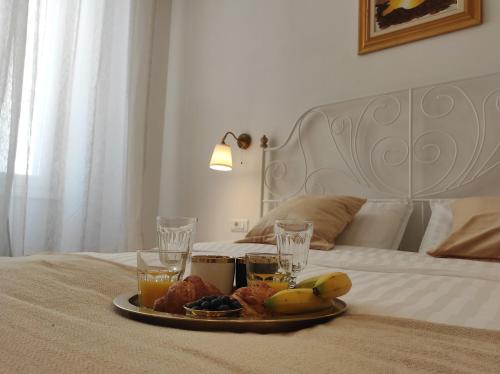 a tray of fruit and drinks on a bed at Papavero rooms in Pula