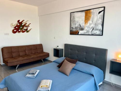 a bedroom with a blue bed and a couch at FatCow Seaside Suites in Livadhia